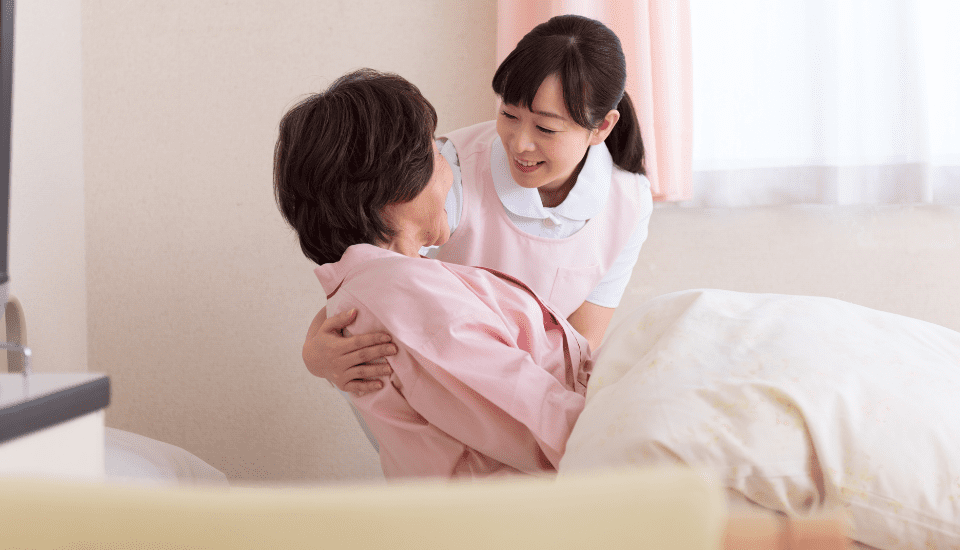 介護職員が入居者を介助している様子。居室内でのケアシーン。